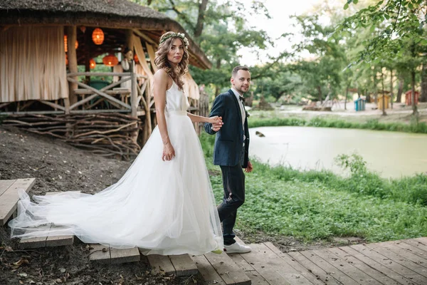 Noiva e noivo no dia do casamento andando ao ar livre na natureza de verão. Casal nupcial, mulher recém-casada feliz e homem abraçando no parque verde. Casal de amor ao ar livre. Noiva e noivo — Fotografia de Stock