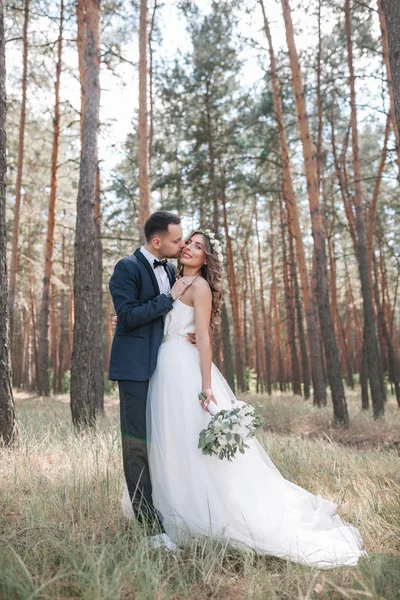 Braut und Bräutigam am Hochzeitstag beim Wandern in der Natur im Sommer. Brautpaar, glückliche frisch vermählte Frau und Mann umarmen sich im grünen Park. Liebendes Hochzeitspaar im Freien. Brautpaar — Stockfoto