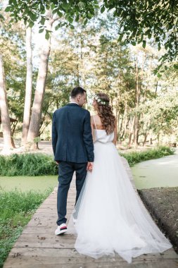 Gelin ve damat gün açık havada yaz doğa üzerinde yürüme düğününde. Gelin Çift, mutlu yeni evli kadın ve yeşil park kucaklayan adam. Sevgi dolu evlilik çift açık. Gelin ve damat