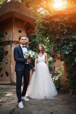 Gelin ve damat gün açık havada yaz doğa üzerinde yürüme düğününde. Gelin Çift, mutlu yeni evli kadın ve yeşil park kucaklayan adam. Sevgi dolu evlilik çift açık. Gelin ve damat