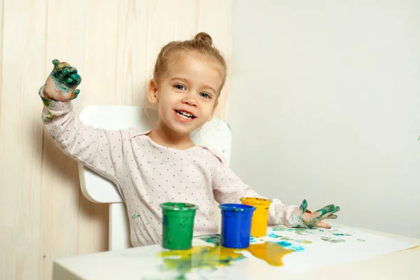 Mooi meisje tekent met de vinger de verf op een wit vel papier. De ontwikkeling van het creatieve kind in de kleuterschool of vrije tijd thuis — Stockfoto