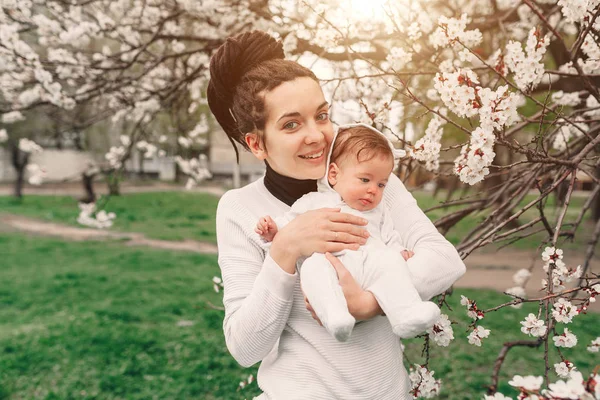 Young mother with adorable daughter in park with blossom tree. Happy mother and child — Stock Photo, Image