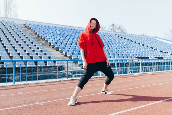 Hermosa chica en ropa deportiva de pie en la pista de atletismo y preparándose para correr. Calentamiento matutino antes del ejercicio . — Foto de Stock