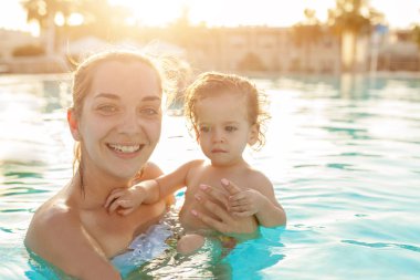 Anne ve küçük kızı Açık Yüzme havuzunda oynanır. Sıcak ülkelerde tatil çocuk ailesiyle. Pozitif kişi tatil.