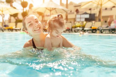 Anne ve küçük kızı Açık Yüzme havuzunda oynanır. Sıcak ülkelerde tatil çocuk ailesiyle. Pozitif kişi tatil.