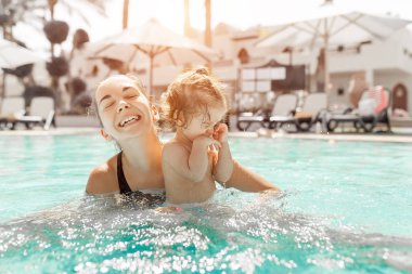 Anne ve küçük kızı Açık Yüzme havuzunda oynanır. Sıcak ülkelerde tatil çocuk ailesiyle. Pozitif kişi tatil.