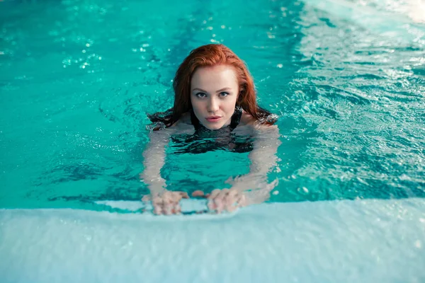 Красивая рыжая девушка-кавказка плавает в крытом бассейне. Здоровый образ жизни . — стоковое фото
