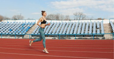 Güneşli sabah sırasında Stadyumu yolda çalışan genç kadın