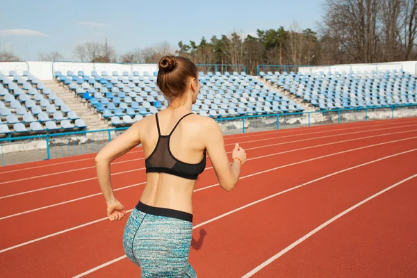 Mladá žena běh během slunečného rána na dráze stadionu — Stock fotografie