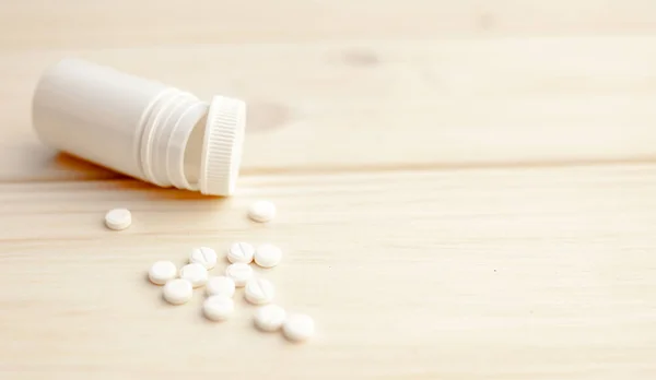 Pillole e bottiglia pillola su sfondo di legno bianco — Foto Stock