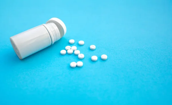 Pillole e bottiglia pillola su sfondo di carta blu — Foto Stock