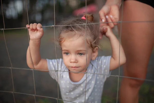 Getinte portret van verdrietig meisje kijkt door draad hek — Stockfoto