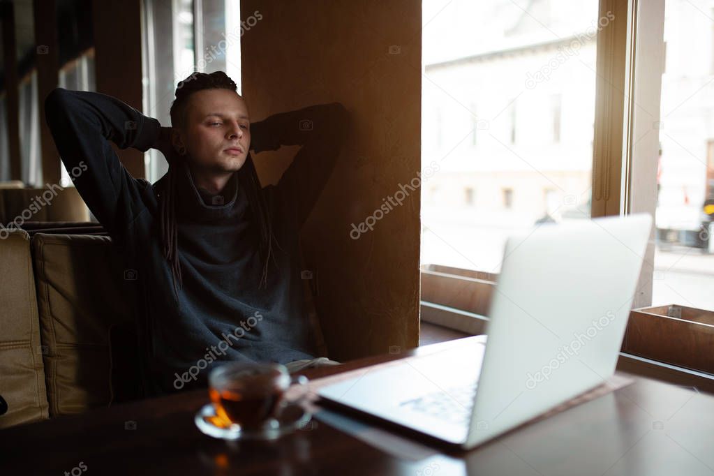 Young Businessman with dreadlock having doing his work in cafe with laptop.