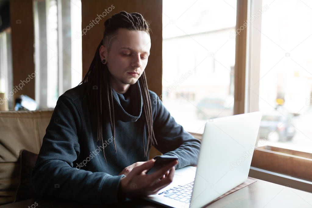 Young Businessman with dreadlock having doing his work in cafe with laptop.