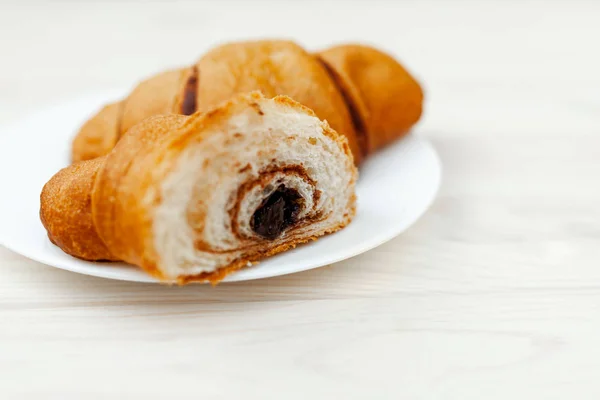 Frisches Croissant mit Schokolade auf weißem Holzhintergrund — Stockfoto