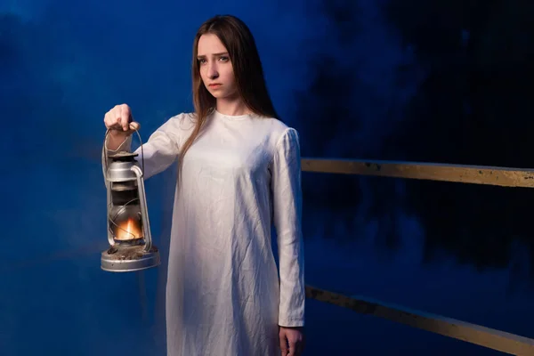 Menina mística misteriosa em uma floresta escura noite com uma lâmpada de querosene em suas mãos — Fotografia de Stock