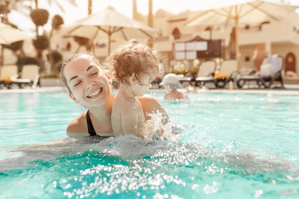 Anne ve küçük kızı Açık Yüzme havuzunda oynanır. Sıcak ülkelerde tatil çocuk ailesiyle. Pozitif kişi tatil.