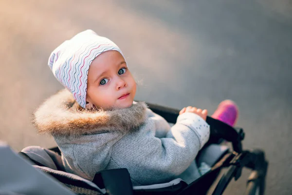 Het kleine meisje keert terug zittend in een kinderwagen op een wandeling in het Park. — Stockfoto