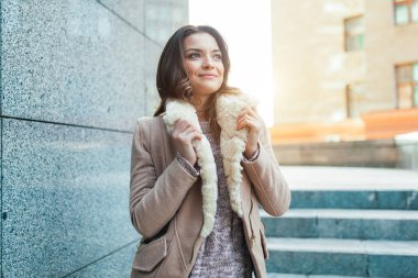 Güzel bir genç esmer kız sıcak güneş ışığı ışınları ile sonbahar şehir boyunca yürür