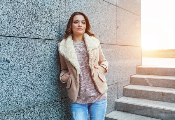 Une belle jeune fille brune se promène dans la ville d'automne sous les rayons du soleil chaud — Photo