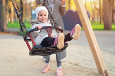 Gün batımında salıncakta mutlu çocuk kız. Küçük çocuk doğa parkında sonbaharda oynuyor