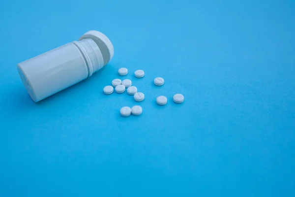 Pillole e bottiglia pillola su sfondo di carta blu — Foto Stock