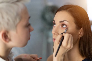 Parlak temel rengi göz farı modelinin e üzerinde uygulama makyaj sanatçısı