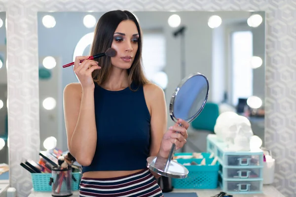 Portrait of pretty female beautician standing posing at workplac