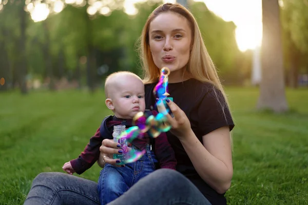Young Caucasian mother inflates soap bubbles with her little son — Stock Photo, Image