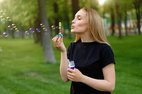 Young beautiful girl inflates soap bubbles in the summer sunny p — Stock Photo, Image