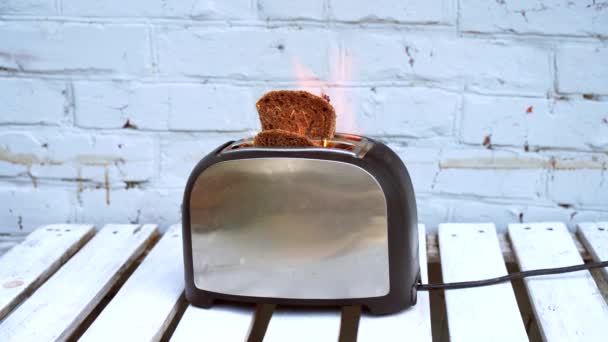 燃えるトースタートーストの2つのスライスが白い背景の上に火に引っ掛かったトースター — ストック動画