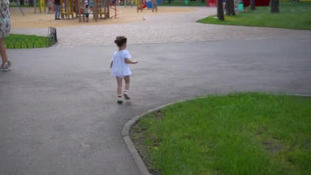 Klein meisje gaat in de speeltuin. Kind buiten spelen in de zomer. Gelukkige kindertijd. — Stockvideo