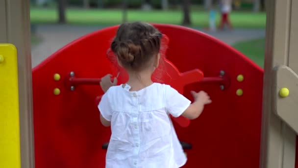 Mała dziewczynka na placu zabaw. Dzieci bawią się na świeżym powietrzu w lecie. Szczęśliwego dzieciństwa. — Wideo stockowe
