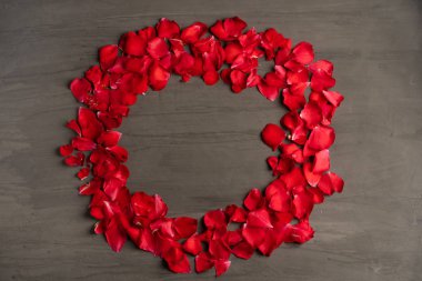 Koyu çimento masa üzerinde gül yapraklarından yapılmış yuvarlak bir çerçeve. 