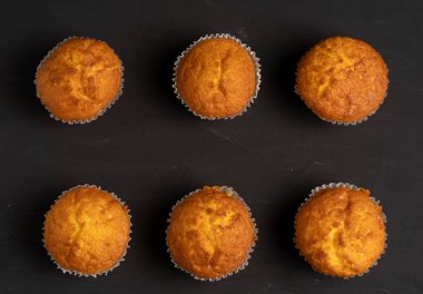 Iştah açıcı muffins bir masa üstü görünümünde duruyor. Koyu bir arka plan minimalizm geleneksel hamur işleri.