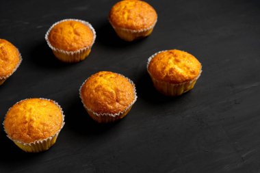 Iştah açıcı muffins bir masa üstü görünümünde duruyor. Koyu bir arka plan minimalizm geleneksel hamur işleri.