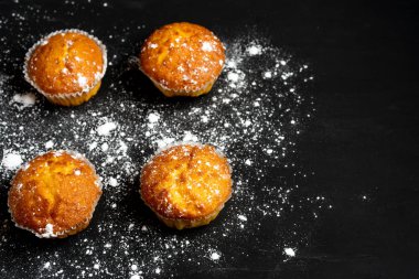 Iştah açıcı muffins bir masa üstü görünümünde duruyor. Koyu bir arka plan minimalizm geleneksel hamur işleri.