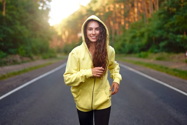 Beautiful caucasian young girl athlete runs sunny summer day on  asphalt road in the forest. — Stock Photo, Image