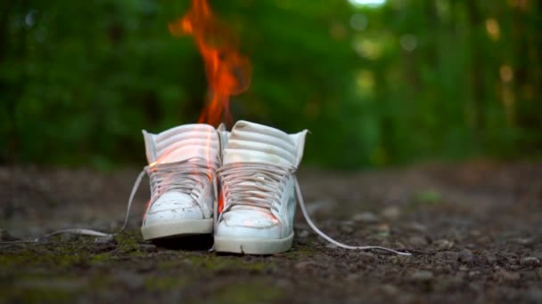 Μεταχειρισμένα λευκά αθλητικά παπούτσια που καίγονται σε έναν αγροτικό δρόμο που τρέχει στο δάσος. — Αρχείο Βίντεο