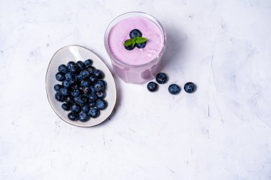Beyaz masa arka planda duran cam lezzetli taze yaban mersini yoğurt sallamak tatlı. 