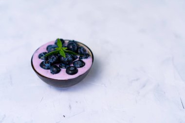 Beyaz masa arka plan üzerinde duran seramik kase lezzetli taze yaban mersini yoğurt sallamak tatlı. 