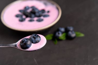 Siyah koyu masa arka planda duran seramik kase lezzetli taze yaban mersini yoğurt sallamak tatlı. 