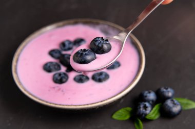 Siyah koyu masa arka planda duran seramik kase lezzetli taze yaban mersini yoğurt sallamak tatlı. 