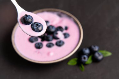 Siyah koyu masa arka planda duran seramik kase lezzetli taze yaban mersini yoğurt sallamak tatlı. 