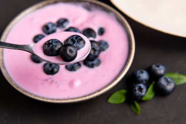 Siyah koyu masa arka planda duran seramik kase lezzetli taze yaban mersini yoğurt sallamak tatlı. 