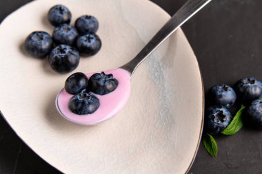 Siyah koyu masa arka planda duran seramik kase lezzetli taze yaban mersini yoğurt sallamak tatlı. 