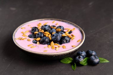 Siyah koyu masa arka planda duran seramik kase lezzetli taze yaban mersini yoğurt sallamak tatlı. 