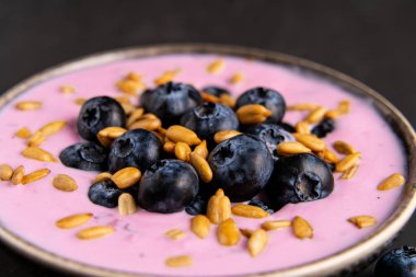 Siyah koyu masa arka planda duran seramik kase lezzetli taze yaban mersini yoğurt sallamak tatlı. 