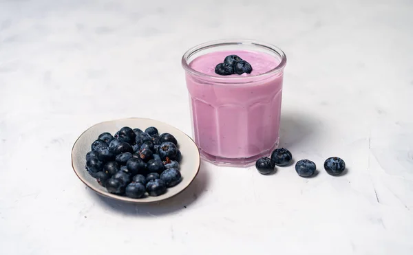 Sabroso yogur de arándano fresco agitar el postre en vidrio de pie sobre fondo de mesa blanca . — Foto de Stock