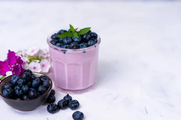 Sabroso yogur de arándano fresco agitar el postre en vidrio de pie sobre fondo de mesa blanca . — Foto de Stock